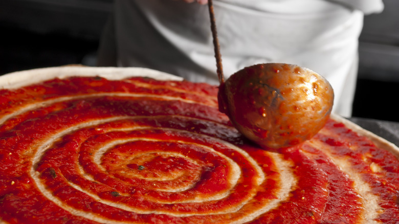 ladling sauce on pizza dough