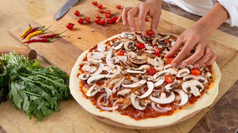 adding toppings to pizza