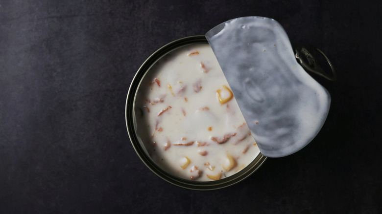 Half-opened can of soup with corn and meat