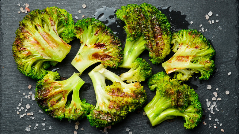 grilled broccoli on a slate with chunks of salt