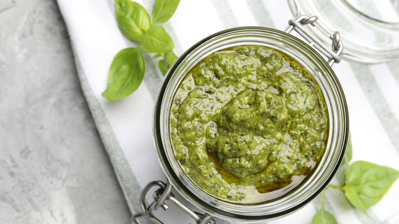 Jar of freshly made pesto sauce against white dish towel
