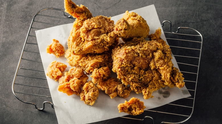 A batch of fried chicken resting on a cooling rack