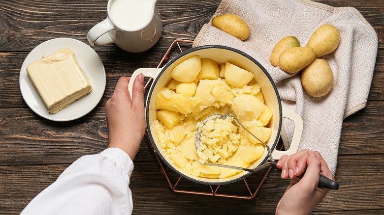 Person mashing pot of potatoes