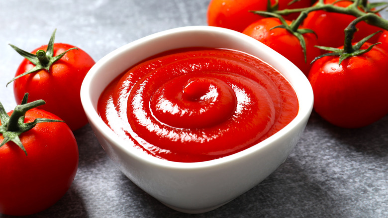 Bowl of ketchup on a counter with tomatoes