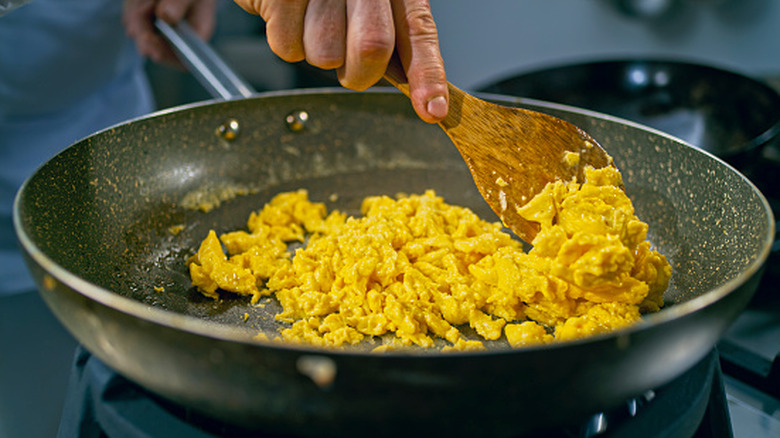 Home cook preparing scrambled eggs in a pan