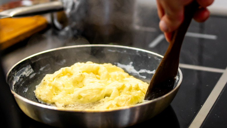 stiring scrambled eggs in pan on stove