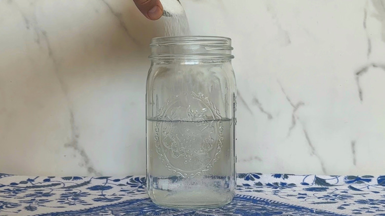 Hand pouring sugar into water