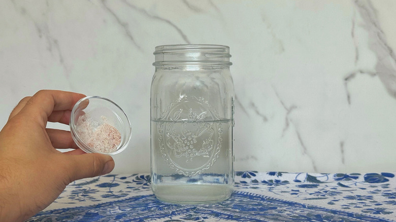 Hand holding salt near jar