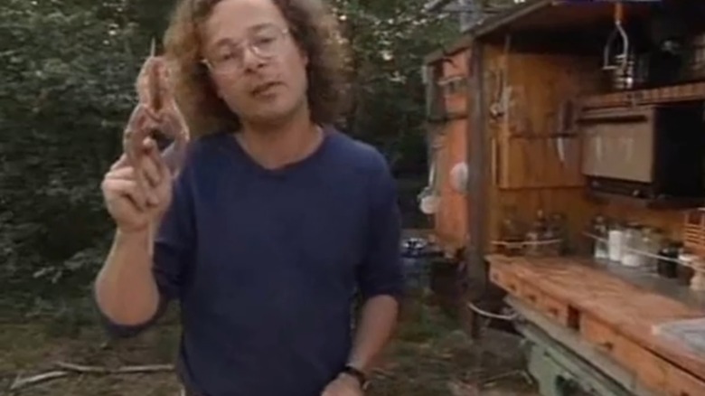 Hugh Fearnley-Whittingstall at an outdoor kitchen holding squirrel meat