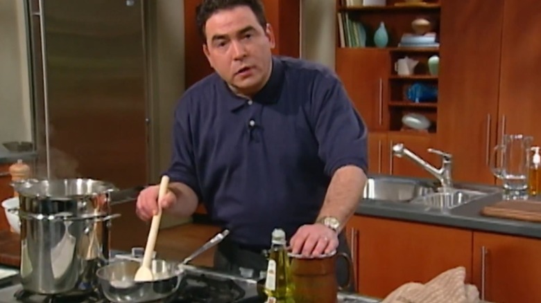 Emeril Lagasse stirring a pan on the stove and looking at the camera