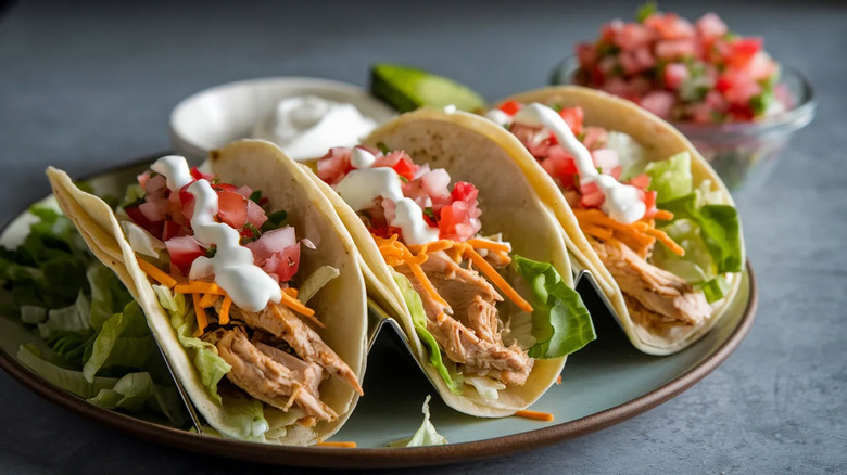 Three pulled chicken tacos with salsa and sour cream