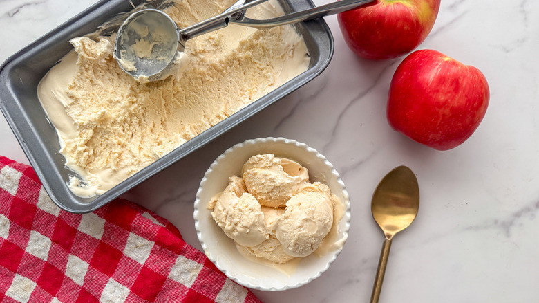 scooper in loaf pan of ice cream next to bowl of ice cream scoops and apples
