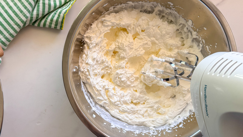 hand mixer beating whipped cream in bowl