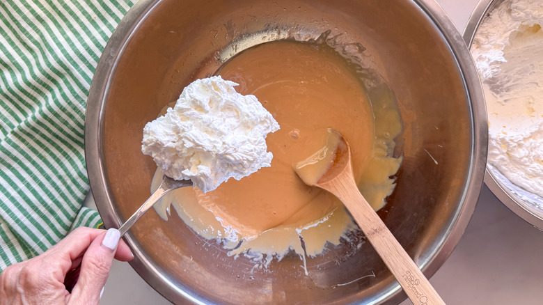 hand adding whipped cream into bowl