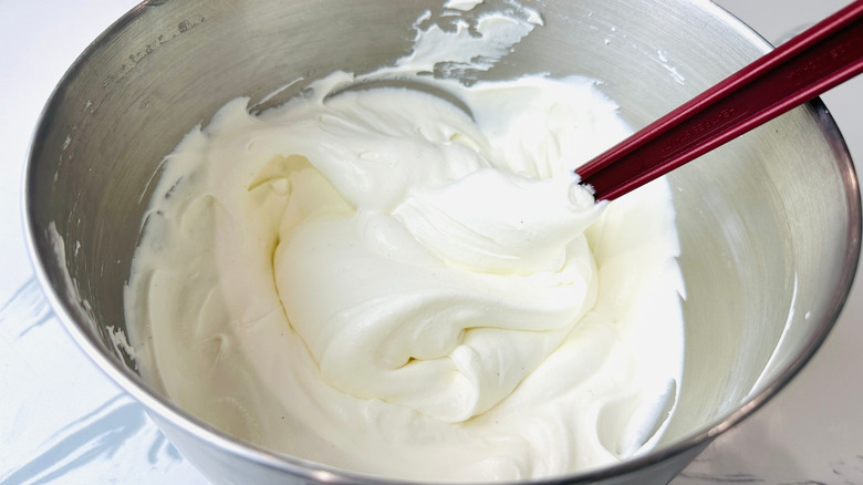 Spatula stirring whipped cream in bowl