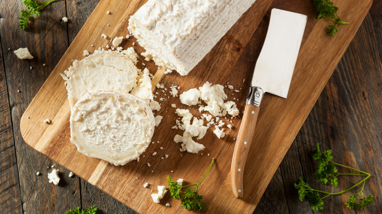 Log of goat cheese on a wooden cutting board