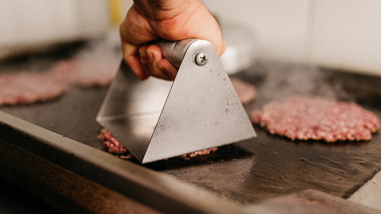 cook smashing a burger patty