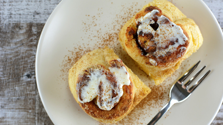 cinnamon rolls are served on plate with a fork.