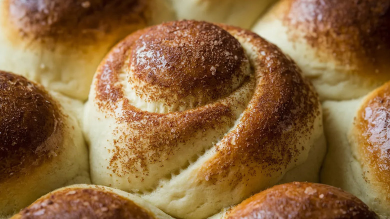 A close up of cinnamon rolls baking together in a pan is shown.