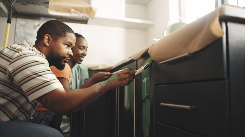 Homeowners painting their kitchen cabinets
