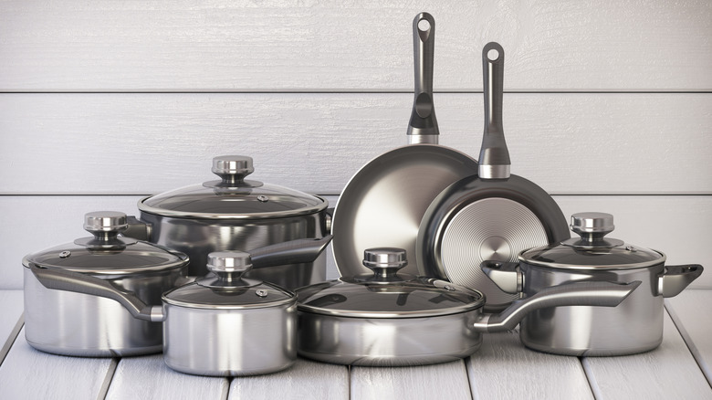 Stainless steel pots and pans in front of white, wooden background