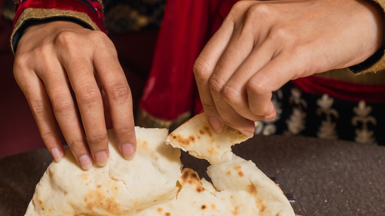 female tearing Indian roti bread
