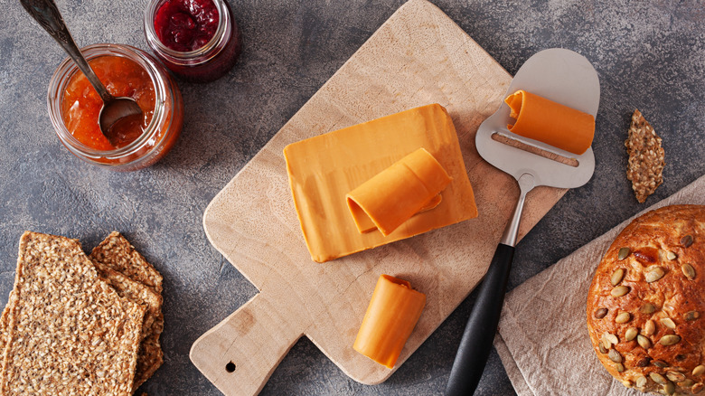 Norwegian brown cheese on a cutting board surrounded by breads and jams