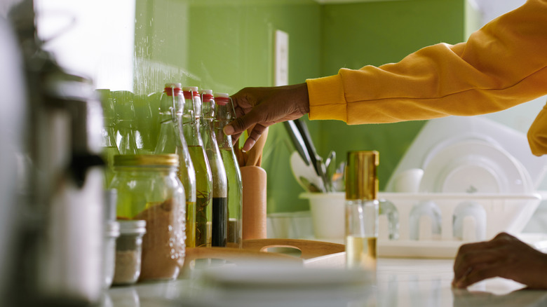 Woman's hand reaching for vinegar bottle on kitchen counter