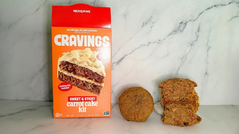 Baked Cravings Carrot Cake Cupcakes sitting next to its box.