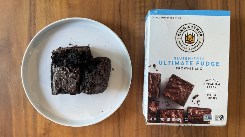 A box of Gluten Free Ultimate Fudge Brownie Mix from King Arthur next to a plate of the baked brownies