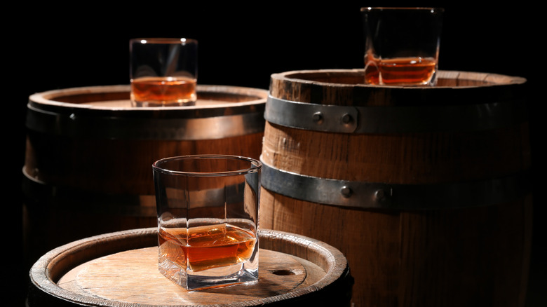 Glasses of whiskey on top of barrels