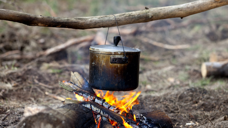 Tin camp kettle cooking over a fire outdoors