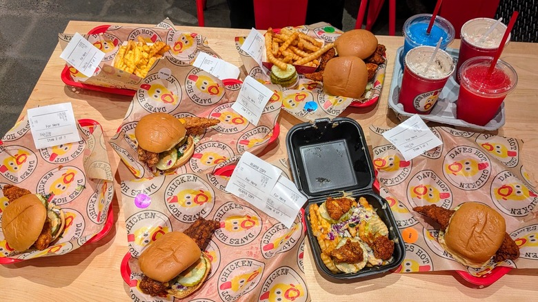Table full of different Dave's Hot Chicken menu items laid out on paper-lined trays