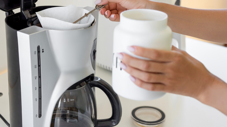 woman putting coffee grounds in a drip coffee machine