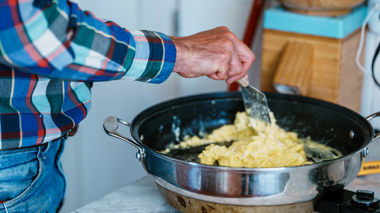 Cowboy scrambling eggs in a farmhouse kitchen