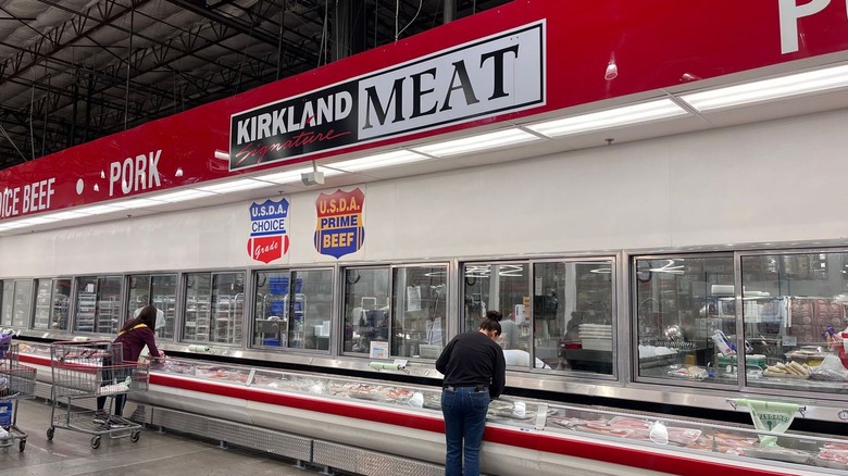Shoppers peruse the refrigerators in the meat section at Costco