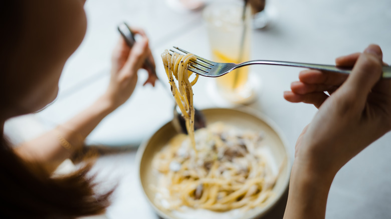 Person eating spaghetti at a table