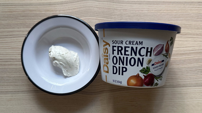 A container of Daisy French onion dip, and a scoop of it in a bowl.