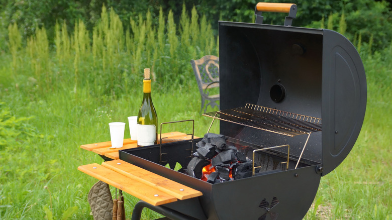 Open barrel charcoal grill in yard