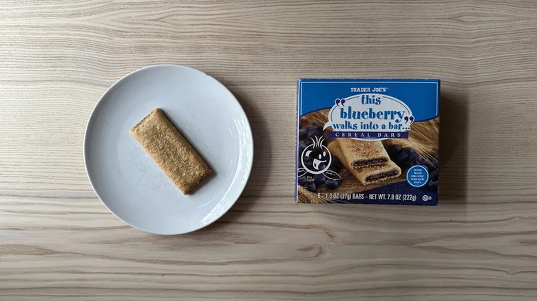 A box of Trader Joe's This Blueberry Walks Into a Bar Cereal Bars with a bar on a plate next to the box