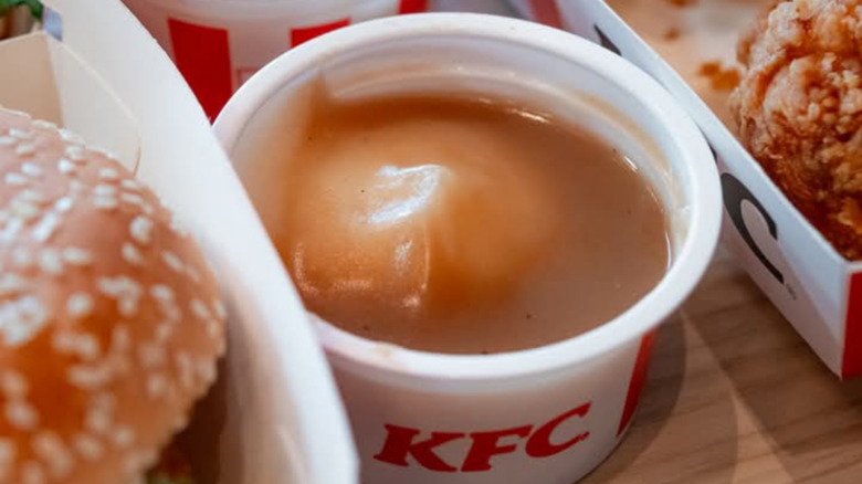 Small container of KFC mashed potatoes and gravy between a container of fried chicken and sandwich