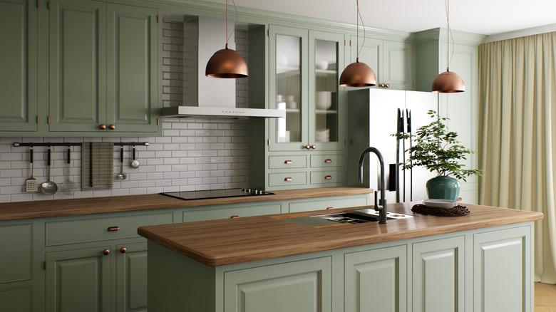 A spacious, open kitchen with modern, raised panel cabinets in a pale green color