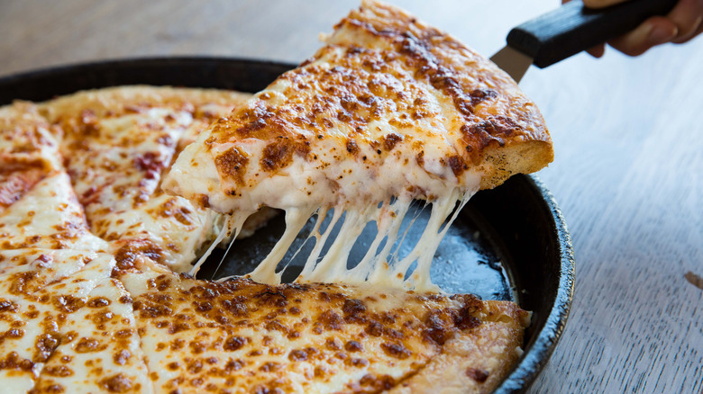 A slice of Pizza Hut pizza being removed from the old cast iron pan