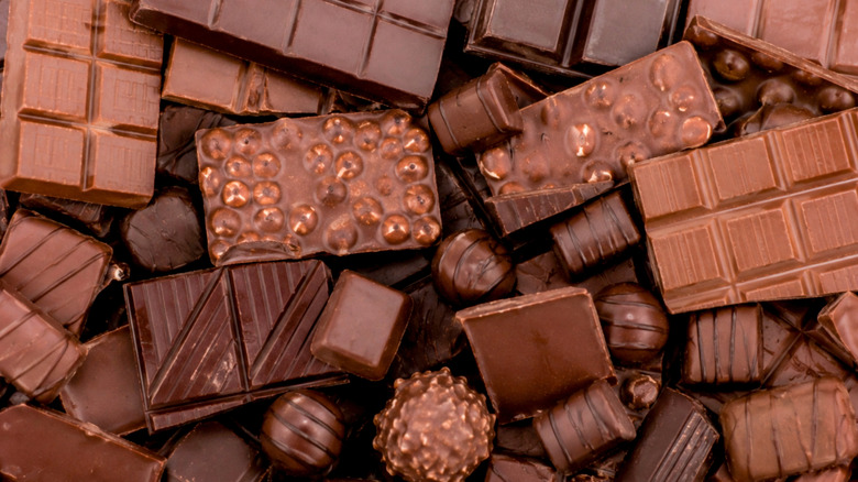 An assortment of unwrapped chocolate bars of various colors and textures.
