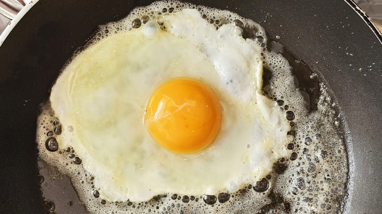 An egg frying in a pan of oil and butter
