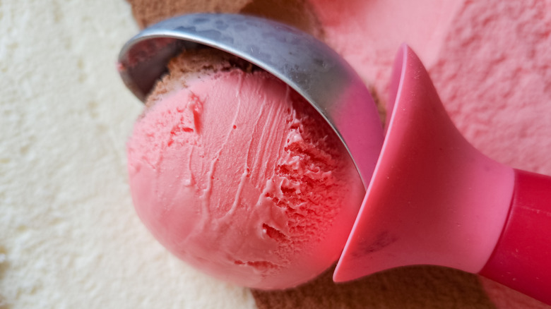Neapolitan ice cream being scooped with a pink ice cream scoop