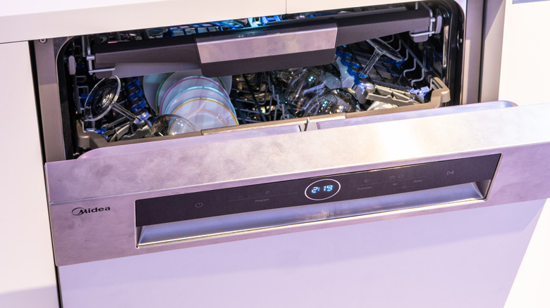 Partially open Midea dishwasher, with dishes inside, and digital time visible on the display screen