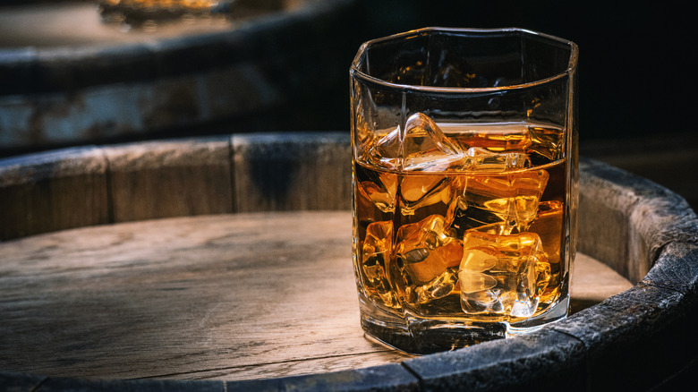 glass of scotch atop barrel