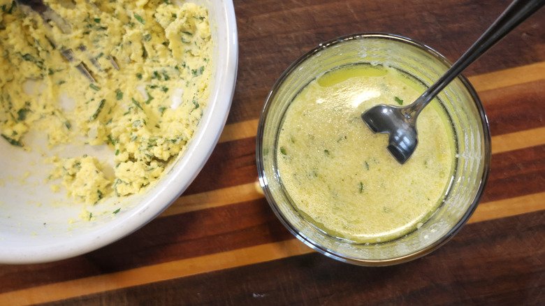 a bowl of vinaigrette beside a bowl of egg yolk paste on a wooden cutting board