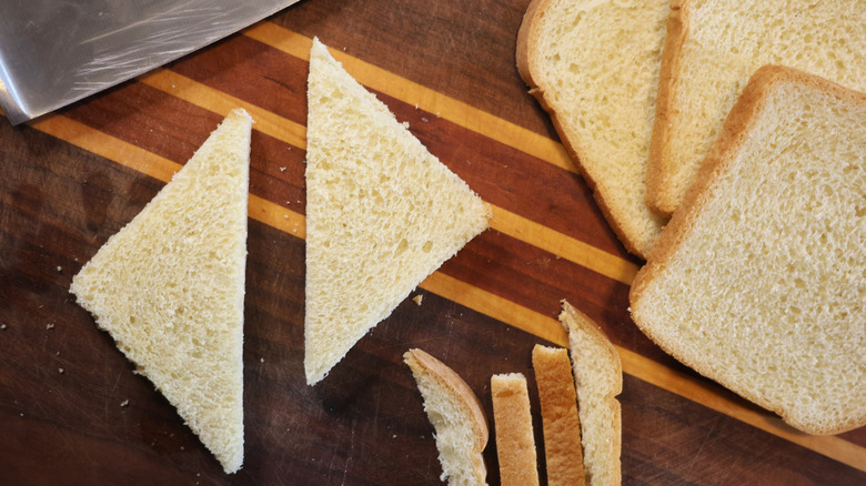 two bread triangles on a cutting board with slices of bread and bread crusts